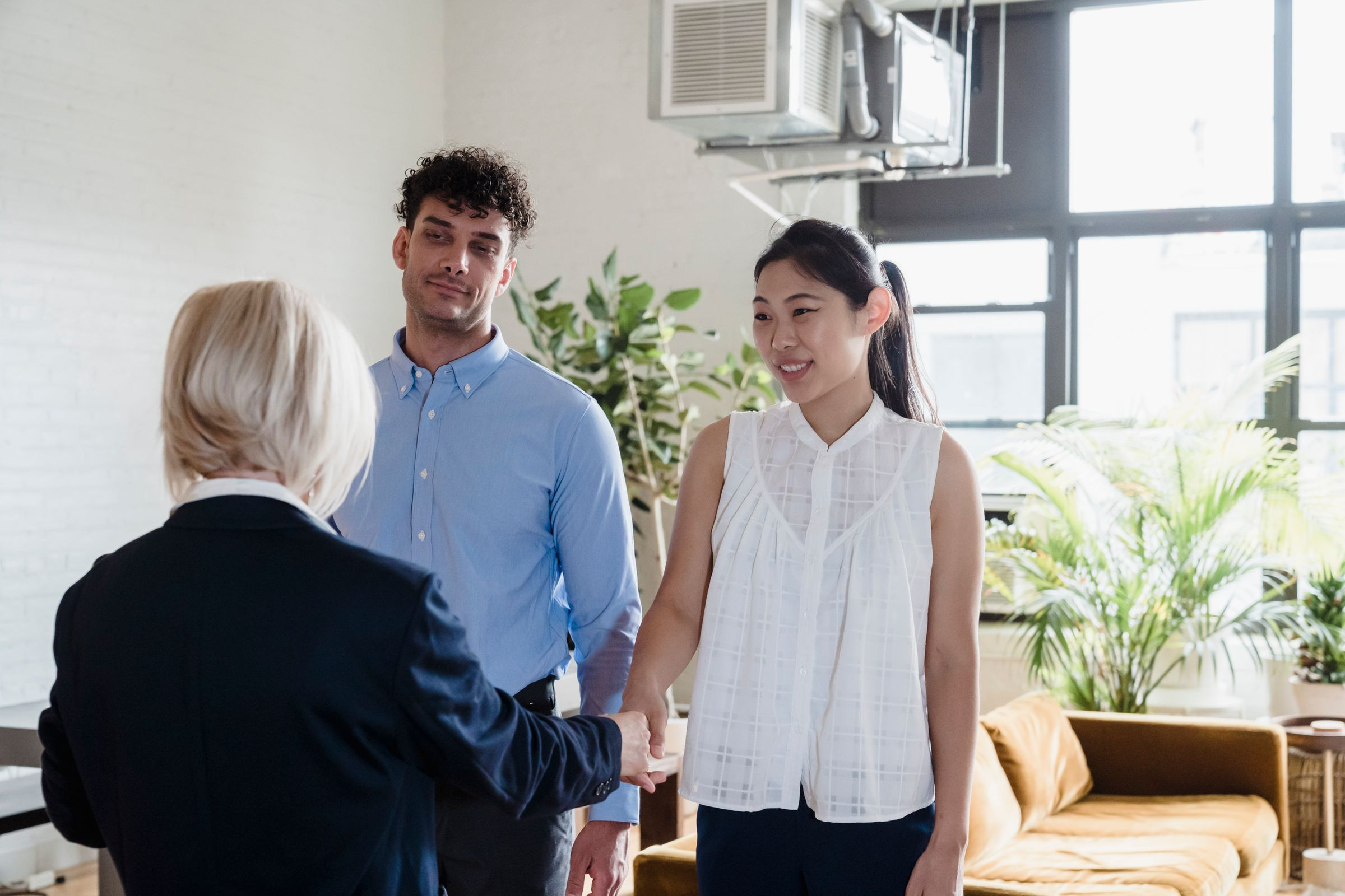 Real estate agent shaking hands with a couple in their new flat